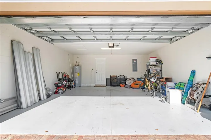 Garage with water heater, electric panel, and a garage door opener
