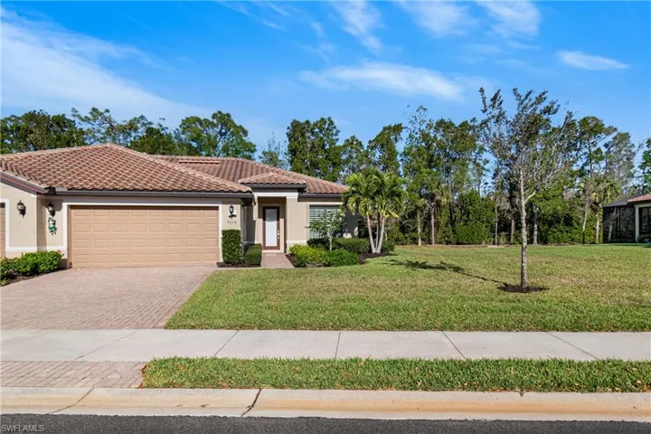 Mediterranean / spanish home with decorative driveway, an attached garage, a front lawn, stucco siding, and a tiled roof