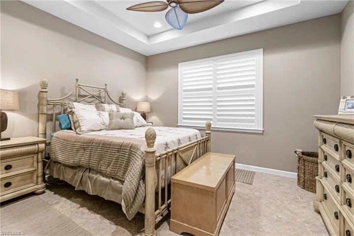Bedroom with a raised ceiling, ceiling fan, and recessed lighting