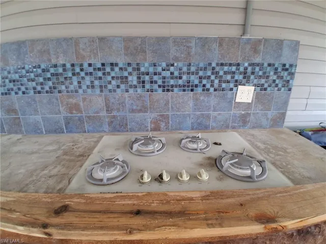 Kitchen view of gas cooktop, backsplash, and wooden counters