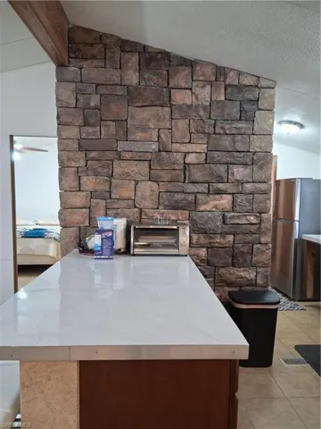 Kitchen view of refrigerator, light countertops, and beam ceiling