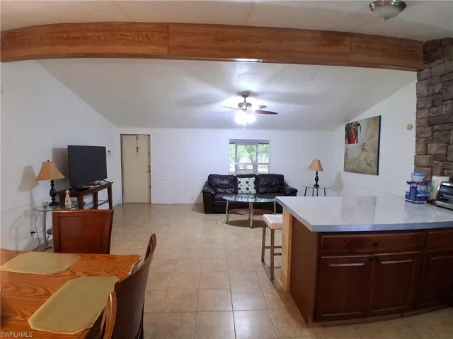 Kitchen with light countertops, a ceiling fan, lofted ceiling with beams, a kitchen breakfast bar, and open floor plan
