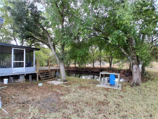 View of yard featuring a deck with water view and a sunroom