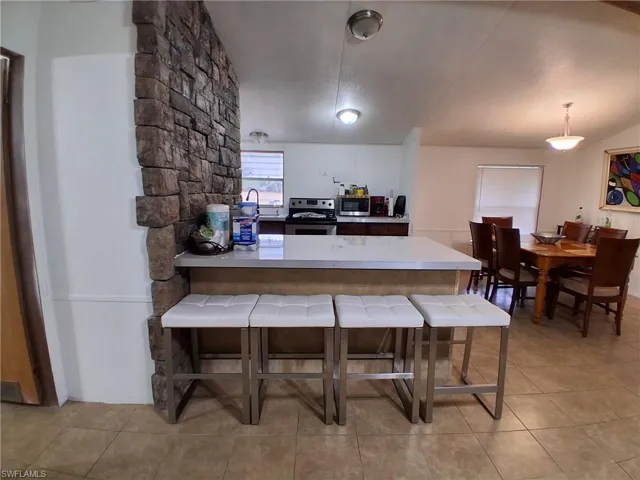 Kitchen featuring a kitchen breakfast bar, stainless steel electric range, light countertops, a peninsula, and hanging light fixtures