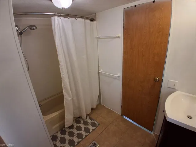Bathroom featuring vanity, shower / bath combo with shower curtain, and tile patterned flooring