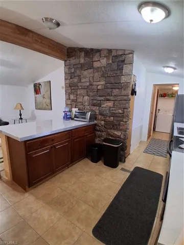 Bar with washer / dryer, light tile patterned floors, beam ceiling, and fridge