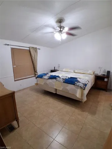 Bedroom featuring a ceiling fan, light tile patterned flooring, and vaulted ceiling