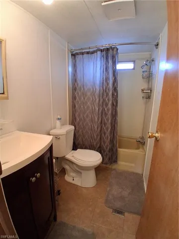 Full bathroom featuring shower / bathtub combination with curtain, vanity, and tile patterned flooring