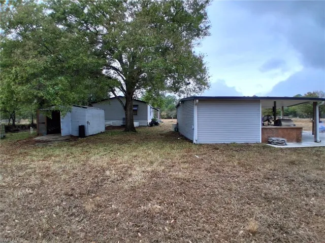 View of grassy yard with a patio area and a storage shed