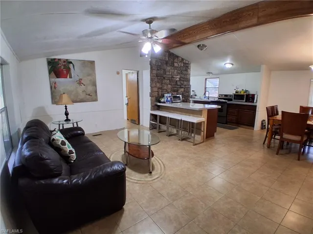 Living area featuring a ceiling fan and beamed ceiling
