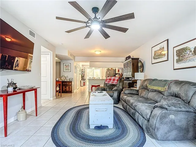 Living room with light tile patterned floors and a ceiling fan