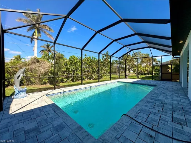 View of pool featuring glass enclosure and a patio area