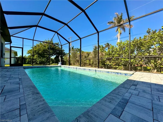 View of swimming pool featuring glass enclosure and a patio