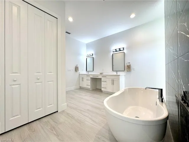 Bathroom with a bath, hardwood / wood-style floors, and vanity