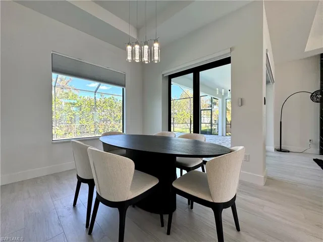 Dining space with a wealth of natural light, light hardwood / wood-style flooring, and a notable chandelier