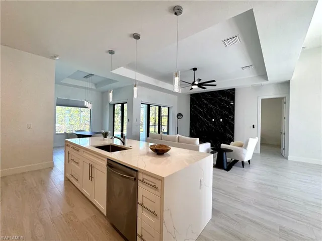 Kitchen with dishwasher, sink, plenty of natural light, and an island with sink