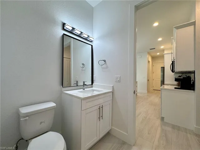 Bathroom with vanity, hardwood / wood-style flooring, and toilet