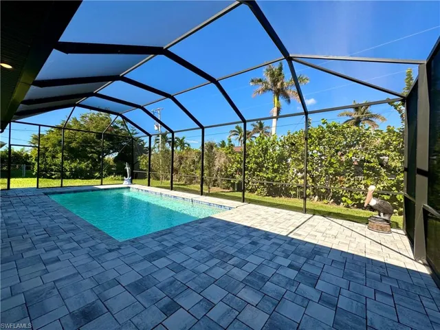 View of swimming pool featuring glass enclosure and a patio