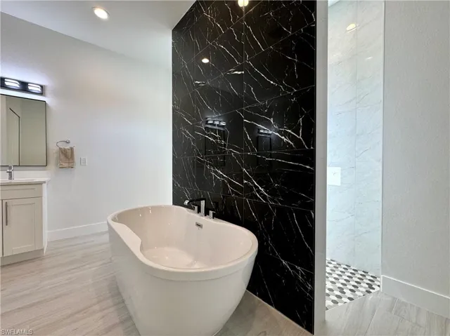 Bathroom with vanity, wood-type flooring, tile walls, and independent shower and bath