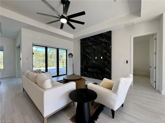 Living room featuring ceiling fan, a raised ceiling, and light hardwood / wood-style flooring