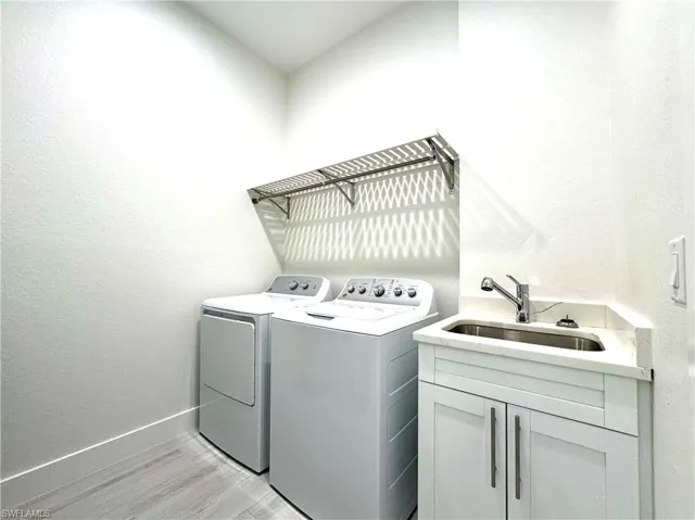 Washroom with washer and dryer, light hardwood / wood-style floors, cabinets, and sink
