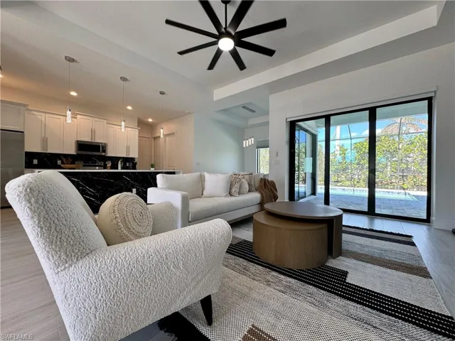 Living room featuring ceiling fan, a raised ceiling, and light wood-type flooring