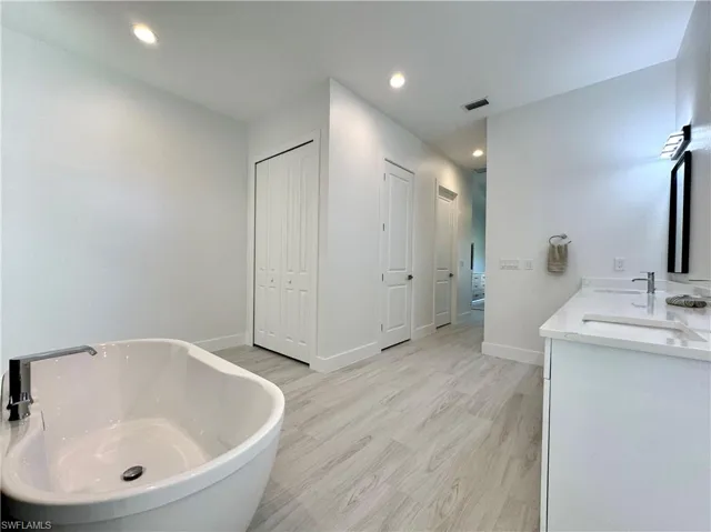 Bathroom with hardwood / wood-style floors, vanity, and a bathtub