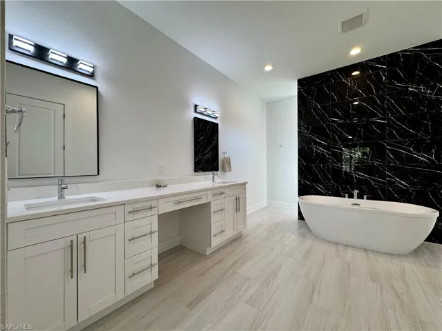 Bathroom featuring vanity, tile walls, and a tub