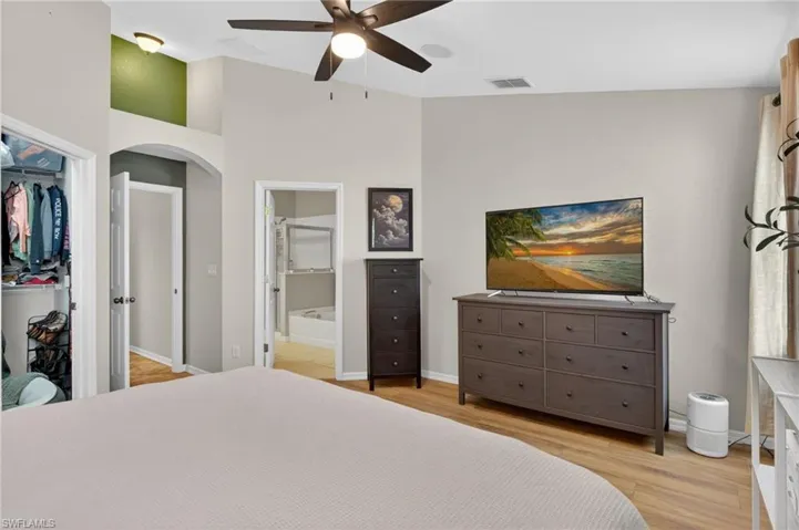 Spacious room featuring vaulted ceilings, wood-finish flooring, a built-in ceiling fan, and an open closet