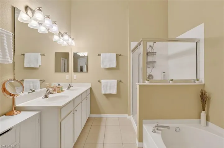 Dual vanity with integrated sinks, white cabinetry, and a full-width mirror