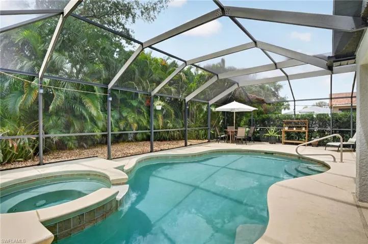 Screened pool enclosure featuring a freeform swimming pool with integrated spa