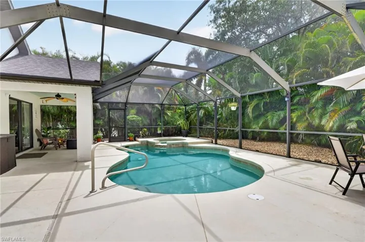 Screened outdoor living area featuring a freeform pool with integrated spa and deck