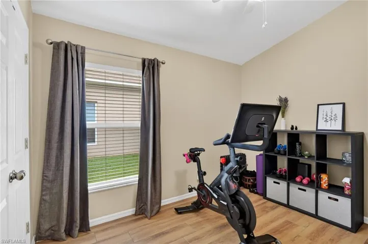 Room featuring wood-finish flooring, a vaulted ceiling, and a large window with blinds