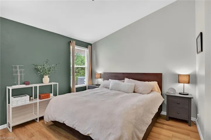 Room featuring wood-finish flooring, a window with blinds, and a built-in wall shelf