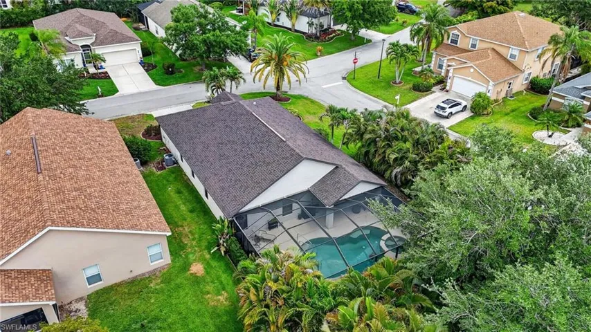 Property featuring a screened-in pool enclosure, shingle roofing, and established landscaping