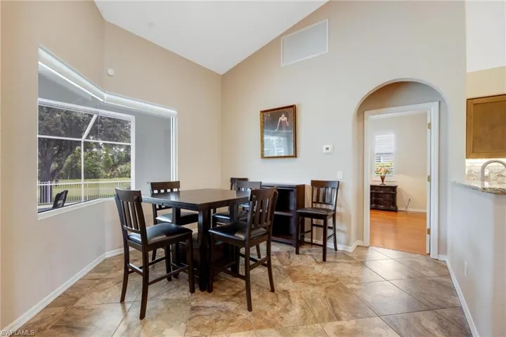 Tiled dining room featuring sink, a wealth of natural light, and high vaulted ceiling