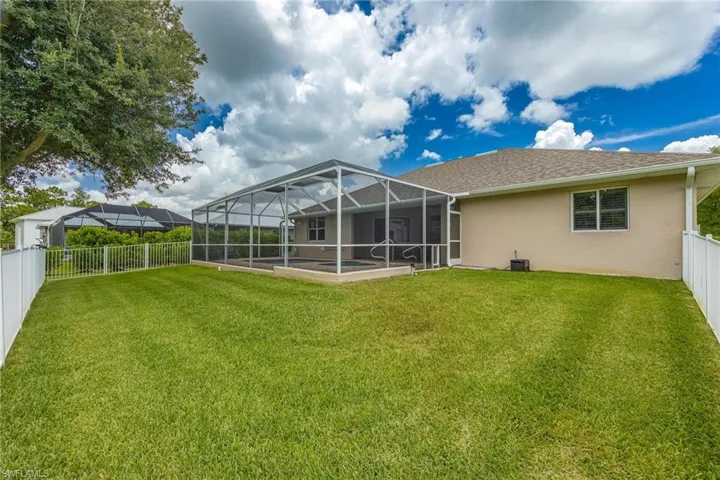 Rear view of house with a lawn and a lanai