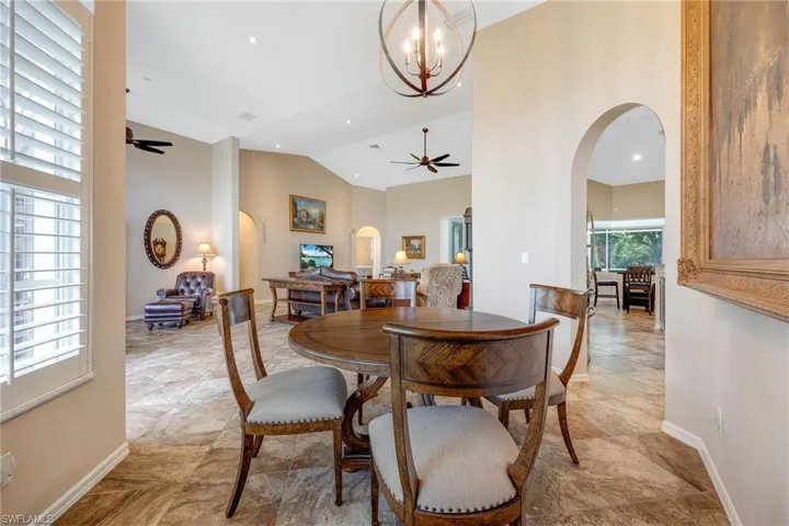 Tiled dining area with high vaulted ceiling and ceiling fan with notable chandelier