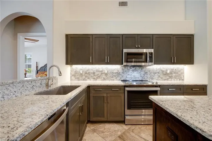 Kitchen with appliances with stainless steel finishes, sink, tasteful backsplash, and light tile flooring
