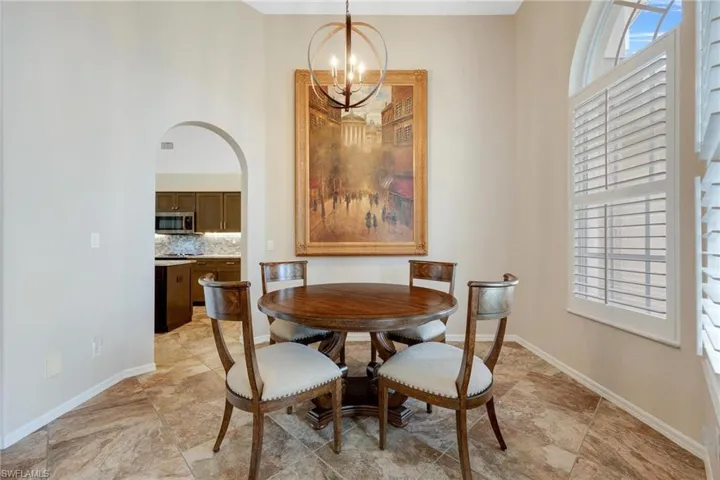Tiled dining room with a towering ceiling and a chandelier