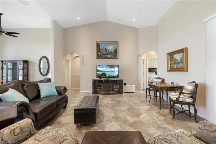Tiled living room with high vaulted ceiling and ceiling fan