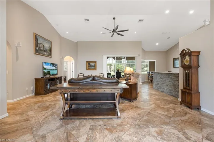 Living room featuring vaulted ceiling, ceiling fan, and light tile flooring