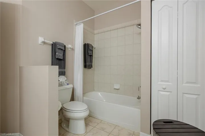 Bathroom featuring tile floors, shower / bath combination with curtain, and toilet