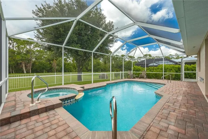 View of pool featuring an in ground hot tub, a lawn, a lanai, and a patio area