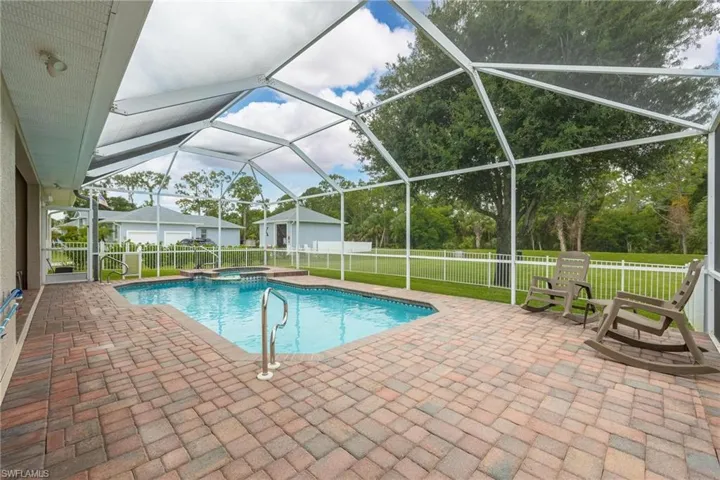 View of swimming pool featuring glass enclosure, a patio area, and a lawn