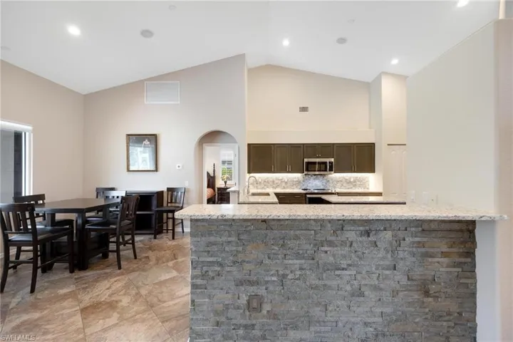 Kitchen featuring light stone countertops, appliances with stainless steel finishes, backsplash, sink, and light tile flooring