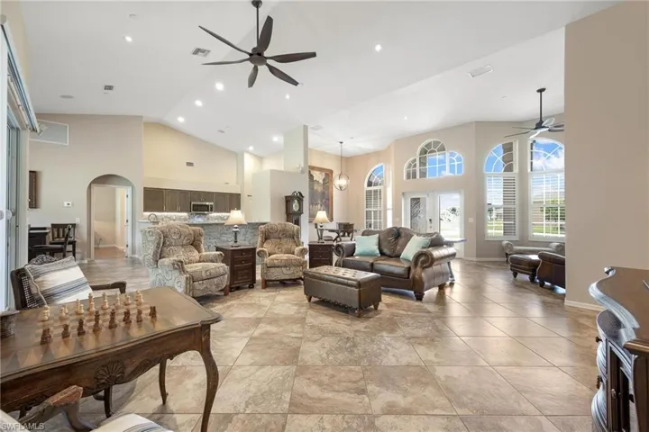Living room with high vaulted ceiling, ceiling fan, and light tile floors