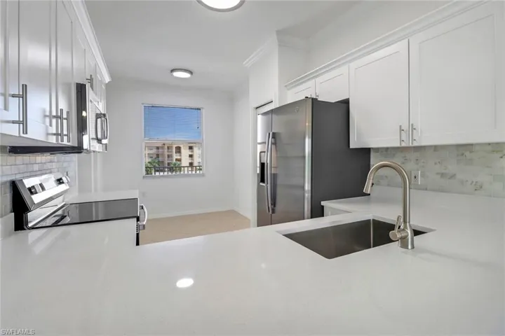 Kitchen with appliances with stainless steel finishes, tasteful backsplash, white cabinets, sink, and light tile patterned floors