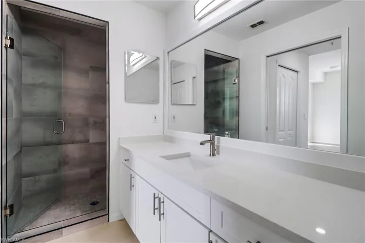 Bathroom featuring tile patterned floors, a shower with door, and vanity