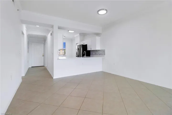 Unfurnished living room with ornamental molding, sink, and light tile patterned flooring